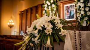 Traditional Puerto Rican funeral service setup with elaborate white gladiola and lily arrangements, rosary beads draped respectfully, warm lighting in Orlando funeral chapel, family photos tastefully displayed